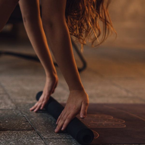 Woman performing a gentle stretching yoga exercise on a mat at home.